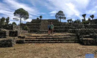 Couple posing for a photo in a ceremonial plaza at Cantona, surrounded by ancient stone architecture and pre-Hispanic landscapes.