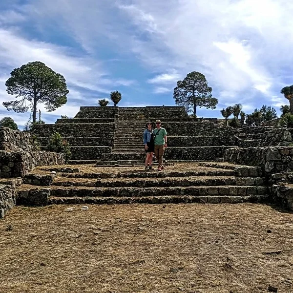 Couple posing for a photo in a ceremonial plaza at Cantona, surrounded by ancient stone architecture and pre-Hispanic landscapes.
