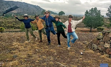 Group of friends celebrating atop one of Cantona’s main pyramids, overlooking ancient stone structures and volcanic landscapes in Puebla, Mexico.