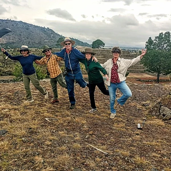 Group of friends celebrating atop one of Cantona’s main pyramids, overlooking ancient stone structures and volcanic landscapes in Puebla, Mexico.