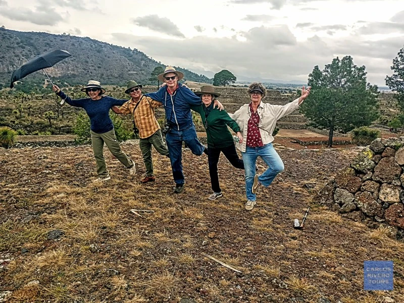 Group of friends celebrating atop one of Cantona’s main pyramids, overlooking ancient stone structures and volcanic landscapes in Puebla, Mexico.