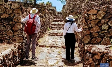 Couple exploring the reconstructed stone street among the ancient ruins of Cantona, Puebla's largest pre-Hispanic city.