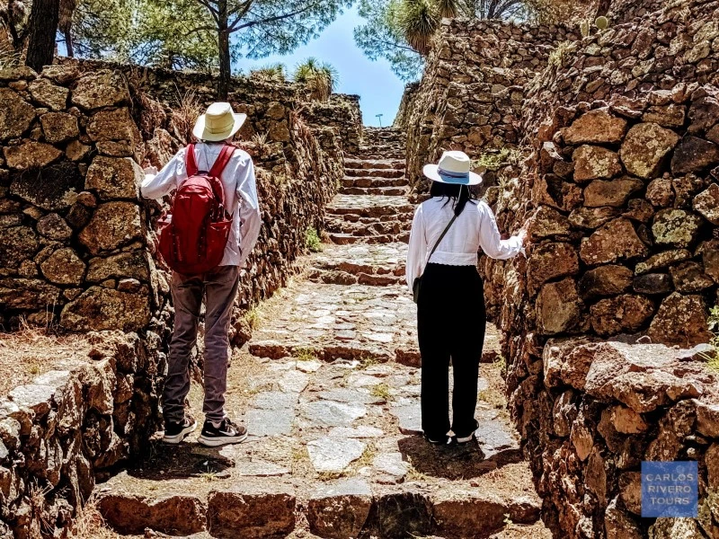 Couple exploring the reconstructed stone street among the ancient ruins of Cantona, Puebla's largest pre-Hispanic city.