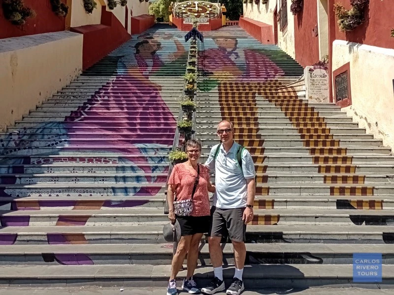 alt="Iconic staircase in Atlixco decorated with colorful murals of local characters, celebrating the town’s artistic identity and community heritage.