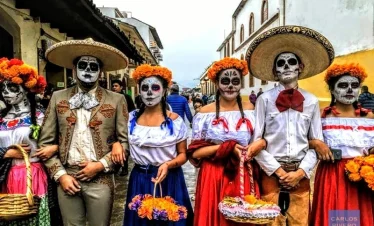 Youth in Mexican regional attire with skull-painted faces during Day of the Dead festivities.