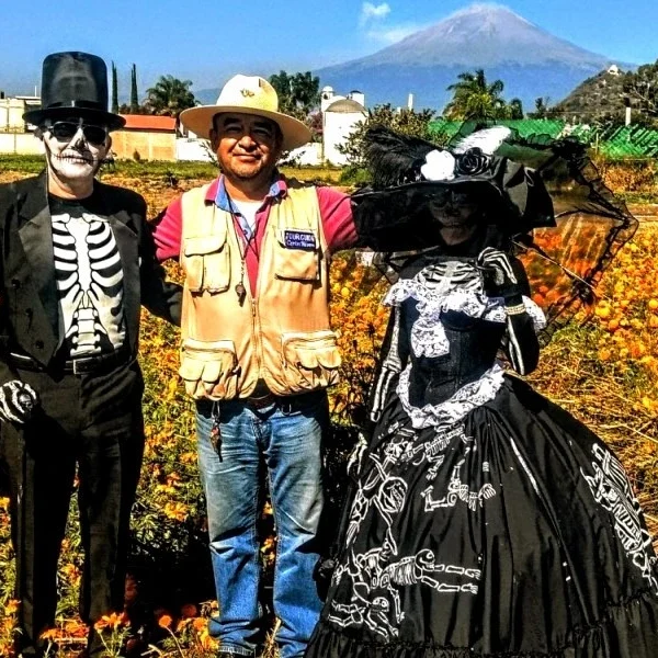 Couple dressed as Catrines with tour guide Carlos Rivero in a cempaxóchitl field near Puebla.