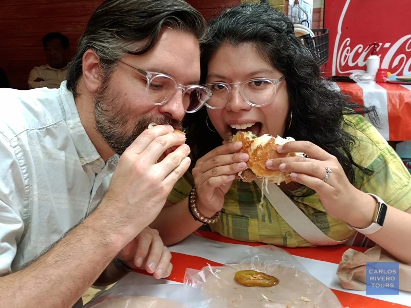 Couple enjoying one of Puebla’s most iconic street food specialties during a walking tour in the historic center, savoring traditional flavors and local atmosphere.