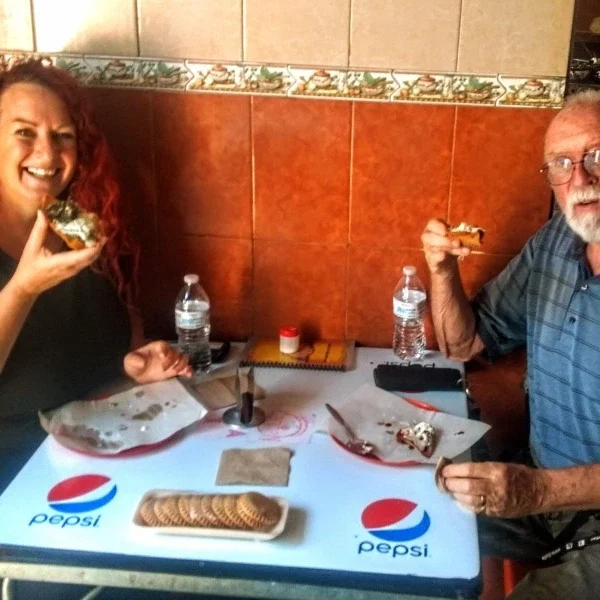 Two friends enjoying another classic Puebla street food specialty during the walking tour, sharing authentic flavors and cultural moments in the historic center.