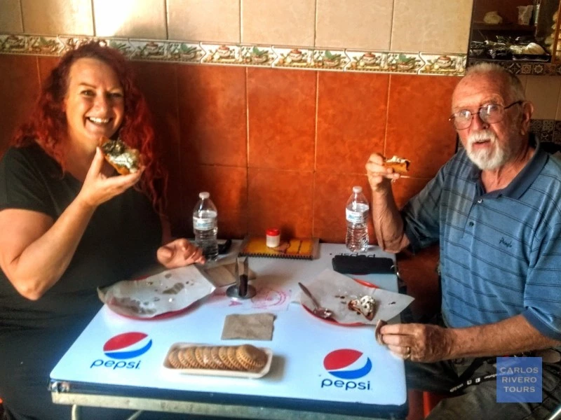 Two friends enjoying another classic Puebla street food specialty during the walking tour, sharing authentic flavors and cultural moments in the historic center.