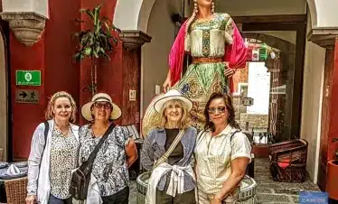 Women enjoying the Puebla City Tour, posing by the Talavera sculpture honoring a famous woman from Puebla, celebrating local artistry, feminine legacy, and urban heritage.