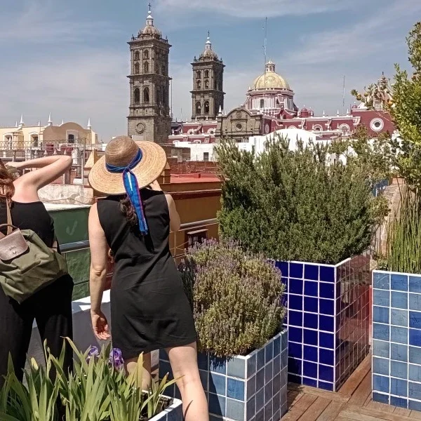 Woman admiring the historic center of Puebla from a scenic rooftop terrace, overlooking colonial architecture and vibrant city views.