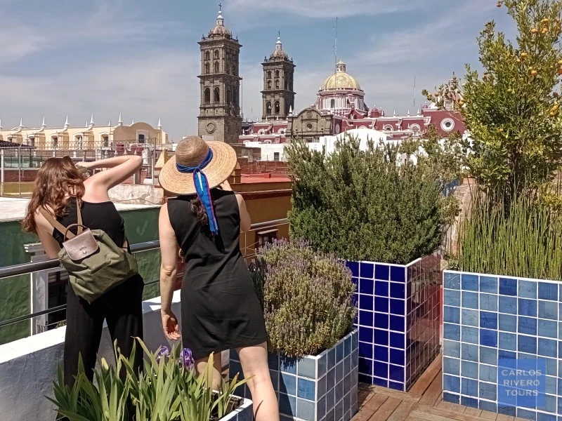 Woman admiring the historic center of Puebla from a scenic rooftop terrace, overlooking colonial architecture and vibrant city views.