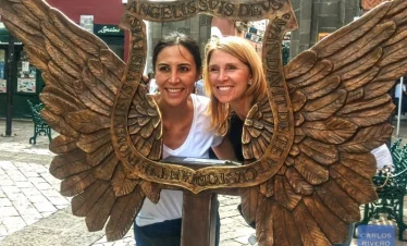 Two female visitors posing with street art referencing Puebla’s original name, Puebla de los Ángeles, a UNESCO World Heritage city known for its colonial legacy.
