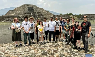 Group of young travelers admiring the view of the Pyramid of the Moon at Teotihuacan, immersed in the ancient atmosphere of Mexico’s iconic archaeological site.