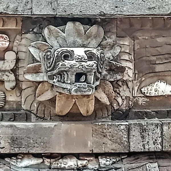 Stone-carved head of the feathered serpent emerging from the Pyramid of the Feathered Serpent at Teotihuacan, symbolizing ancient Mesoamerican mythology and architectural mastery.
