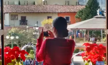 Woman taking photos of the Zócalo in Zacatlán, capturing the charm of this Magic Town with its colonial buildings, floral clock, and festive atmosphere.