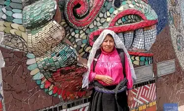 Indigenous woman in traditional attire standing before Zacatlán’s ceramic murals, celebrating regional identity, artisanal heritage, and cultural resilience.