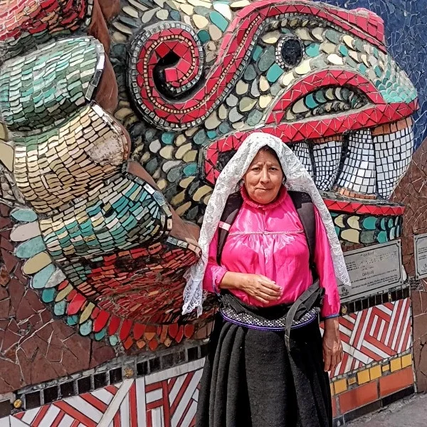 Indigenous woman in traditional attire standing before Zacatlán’s ceramic murals, celebrating regional identity, artisanal heritage, and cultural resilience.