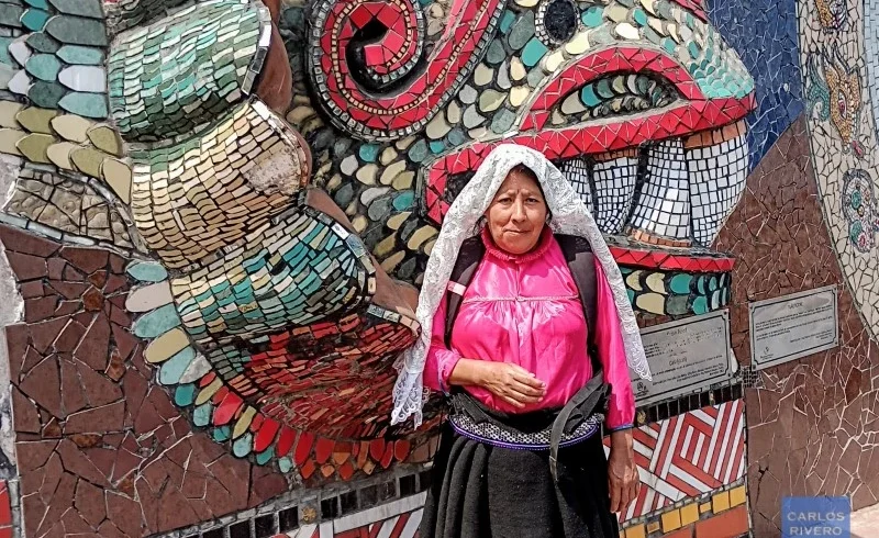 Indigenous woman in traditional attire standing before Zacatlán’s ceramic murals, celebrating regional identity, artisanal heritage, and cultural resilience.
