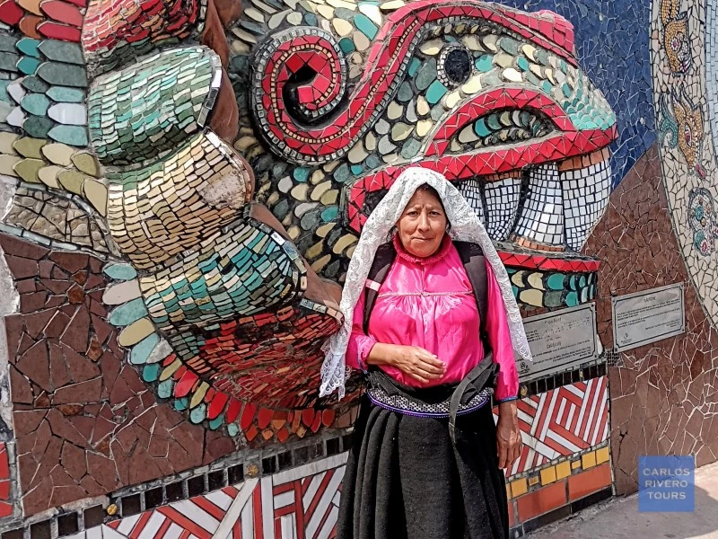 Indigenous woman in traditional attire standing before Zacatlán’s ceramic murals, celebrating regional identity, artisanal heritage, and cultural resilience.