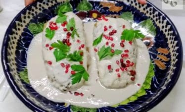 A freshly prepared plate of Chiles en Nogada with walnut cream sauce and pomegranate seeds in Puebla.