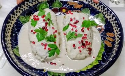 A freshly prepared plate of Chiles en Nogada with walnut cream sauce and pomegranate seeds in Puebla.