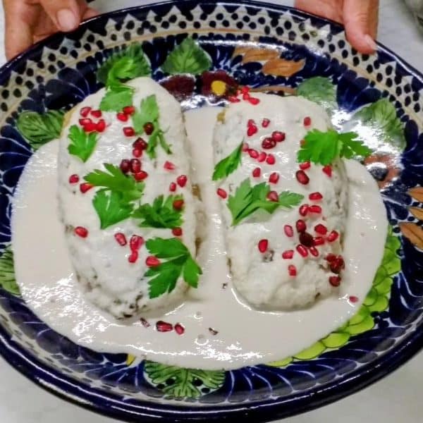 A freshly prepared plate of Chiles en Nogada with walnut cream sauce and pomegranate seeds in Puebla.