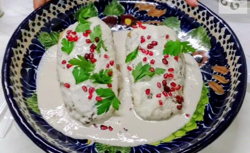 A freshly prepared plate of Chiles en Nogada with walnut cream sauce and pomegranate seeds in Puebla.
