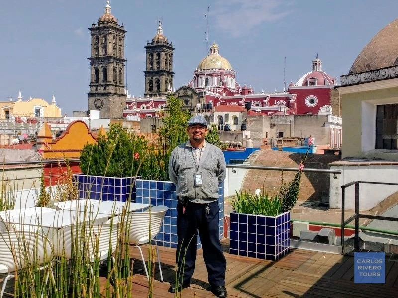 Carlos Rivero, certified cultural guide in Puebla, standing in front of the Cathedral and historic city center during a heritage tourism tour.